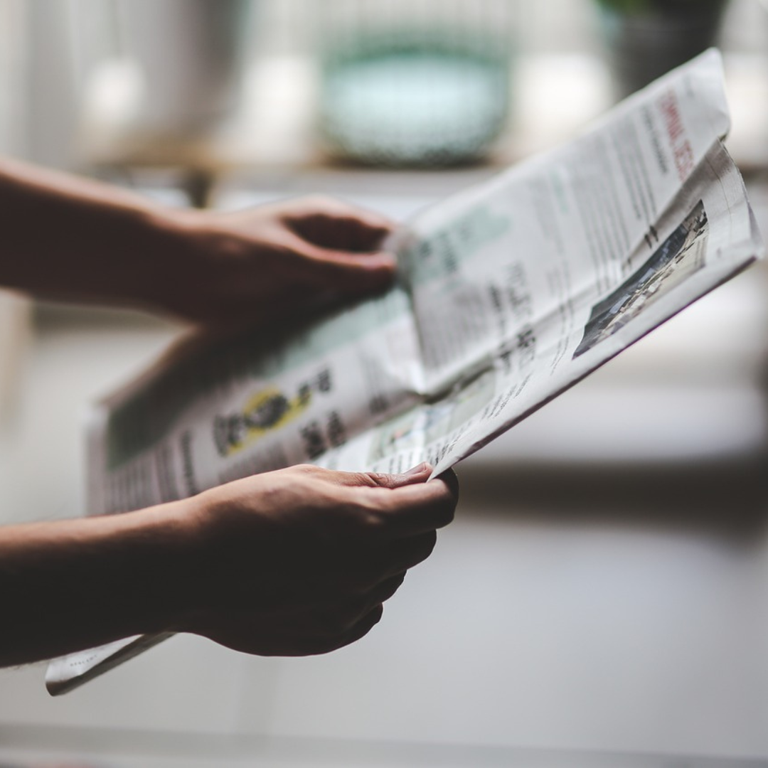 Une personne en train de lire un journal, de type quotidien.