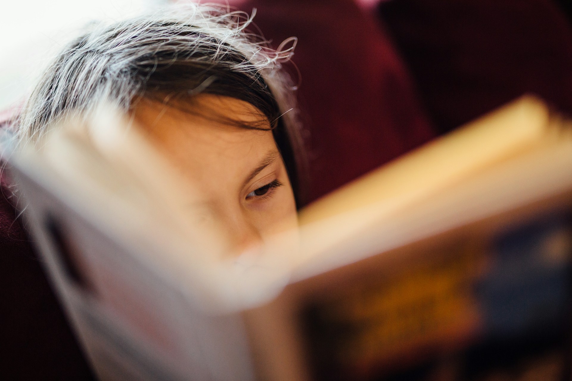 Une enfant semble passionnée par le livre qu'elle tient dans les mains.